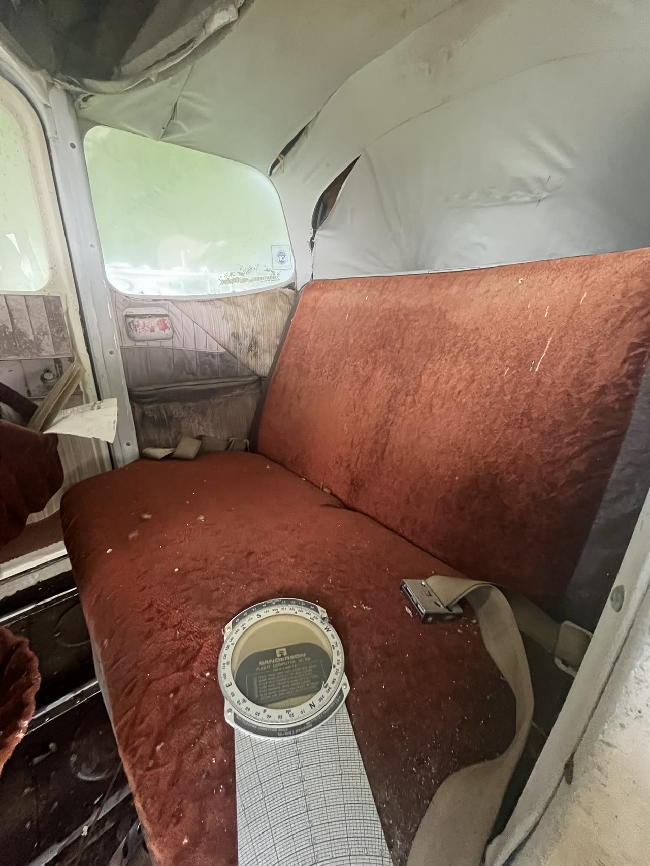 Weathered red cabin seating and interior surfaces inside N8777B before restoration.