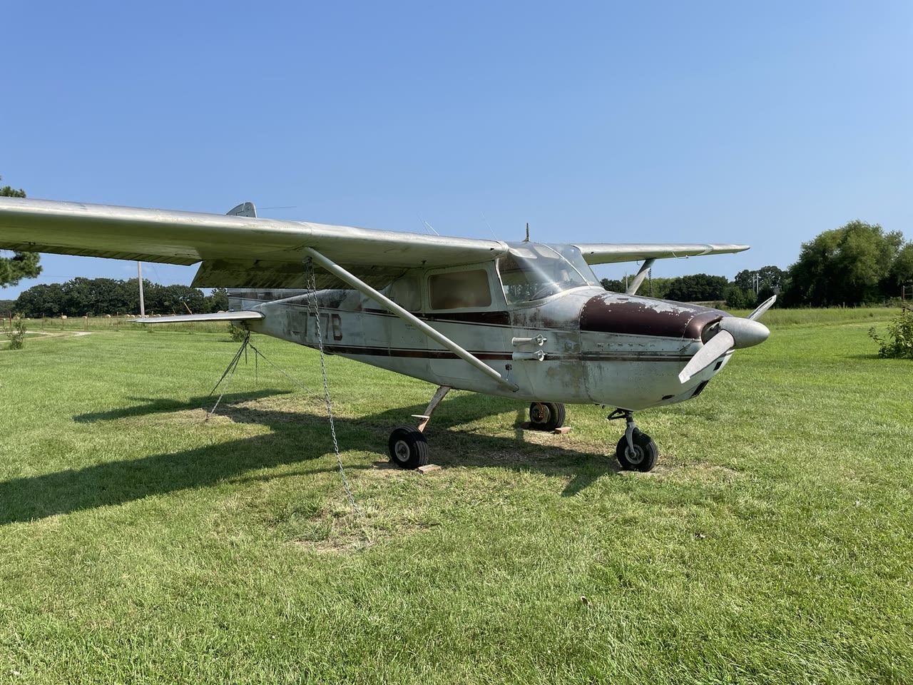 Three-quarter exterior view of Cessna 172 N8777B on grass after its initial professional cleaning, showing the weathered original red-and-white finish.