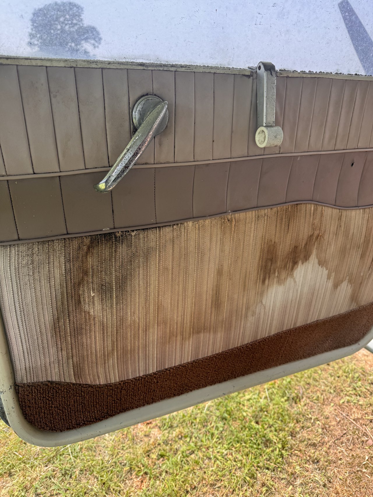 Cabin door panel after initial professional cleaning, showing the cleaned upper panel and remaining permanent staining in the aged lower material.