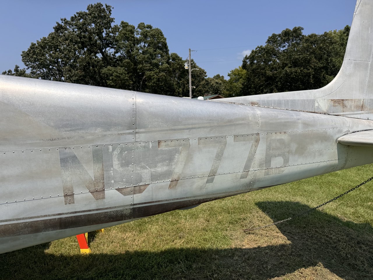 Left tail and fuselage of N8777B after initial professional cleaning, showing reduced surface contamination while the faded original finish remains visible.